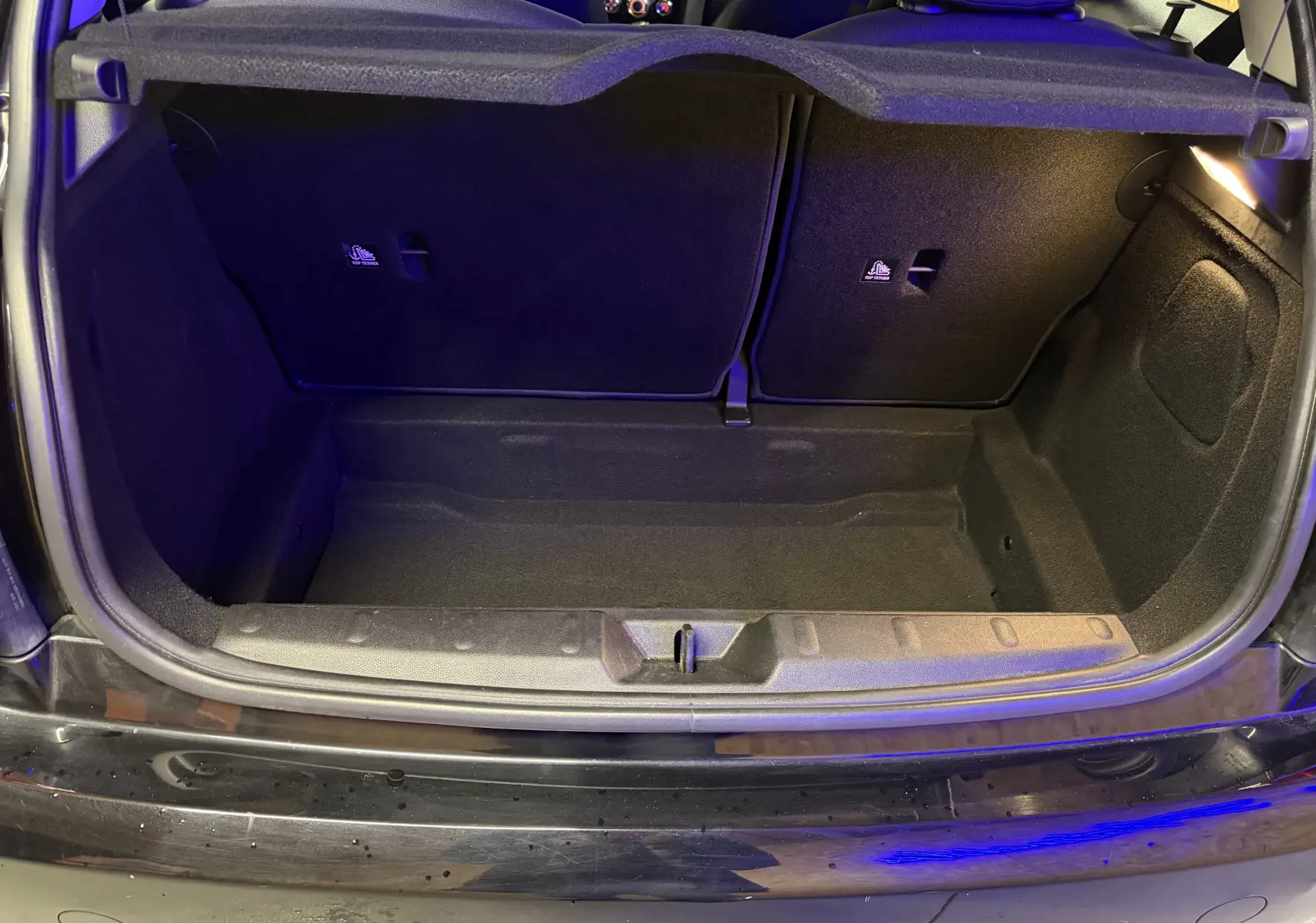 Coffre ouvert vu de l'arrière d'une MINI 1.5i 75CV ONE noire, montrant l'espace de rangement intérieur vide.