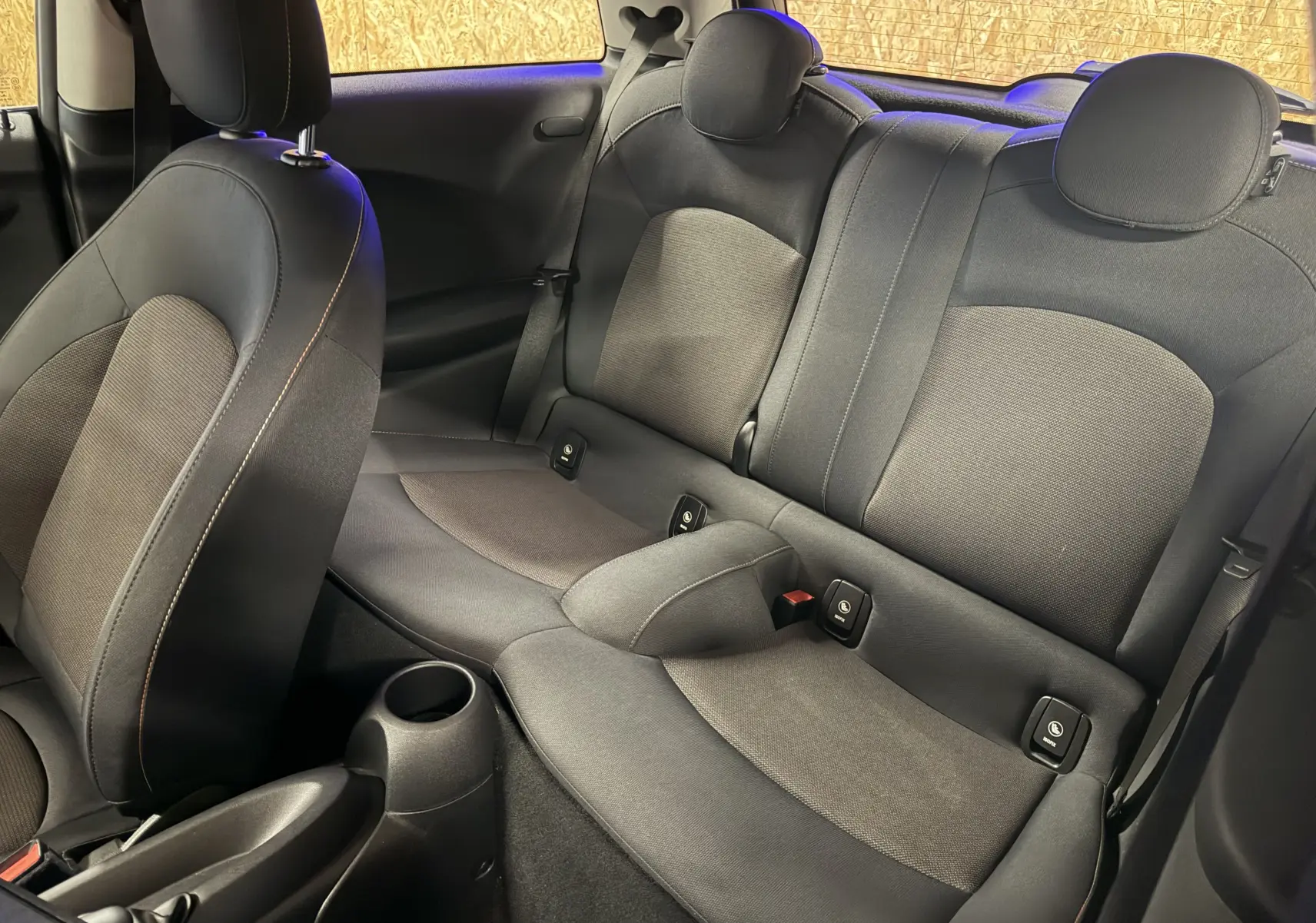 Vue intérieure de la banquette arrière et siège avant gauche d'une MINI noire, avec appuie-têtes et habillage tissu noir.