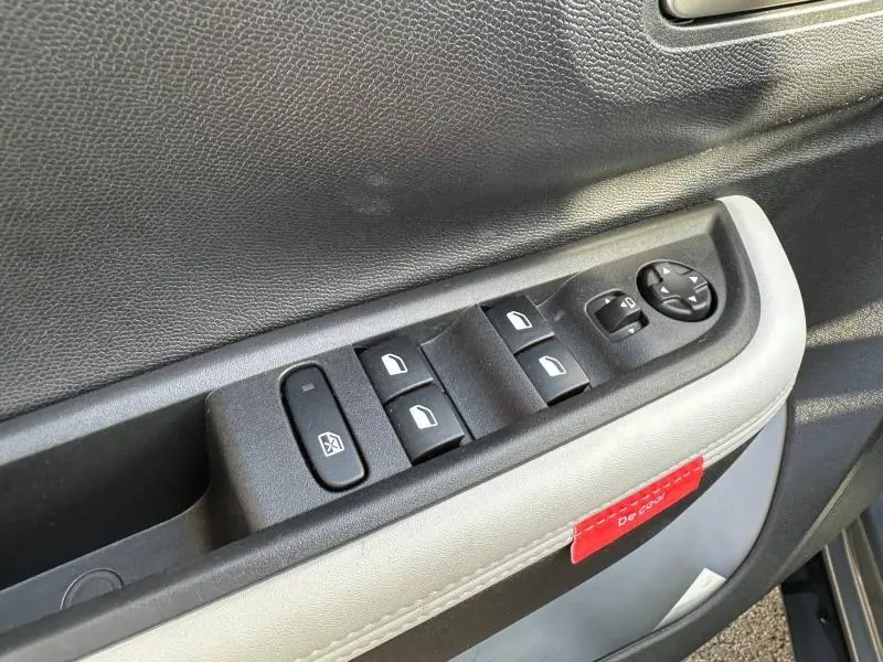 Gros plan sur les commandes des vitres et rétroviseurs sur la porte intérieure gris clair d'une Citroën C3 Gris Mercury 2025.