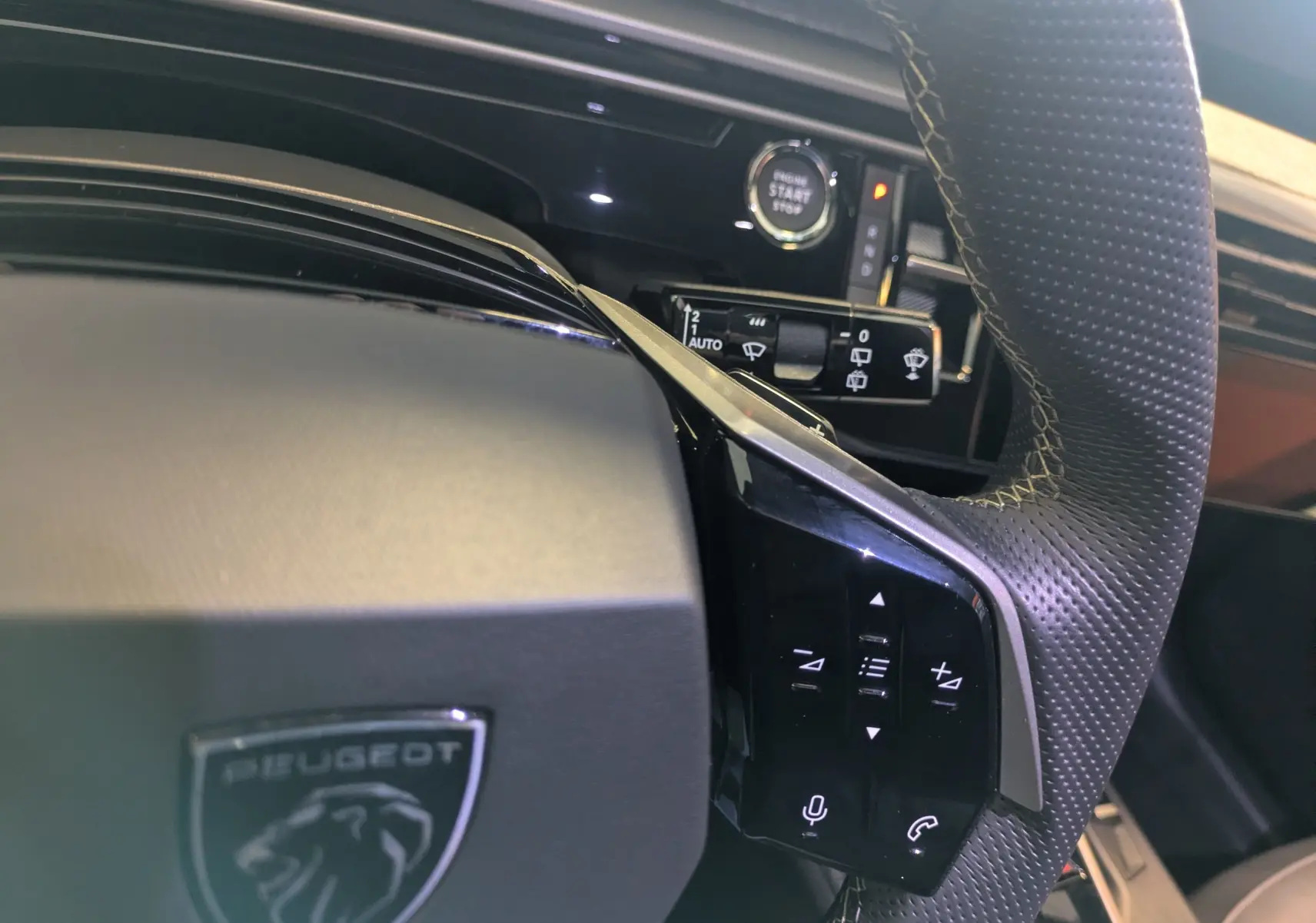 Gros plan sur le volant noir perforé du Peugeot 5008 Hybrid 145 e-DCS6 GT avec commandes tactiles et bouton start/stop.