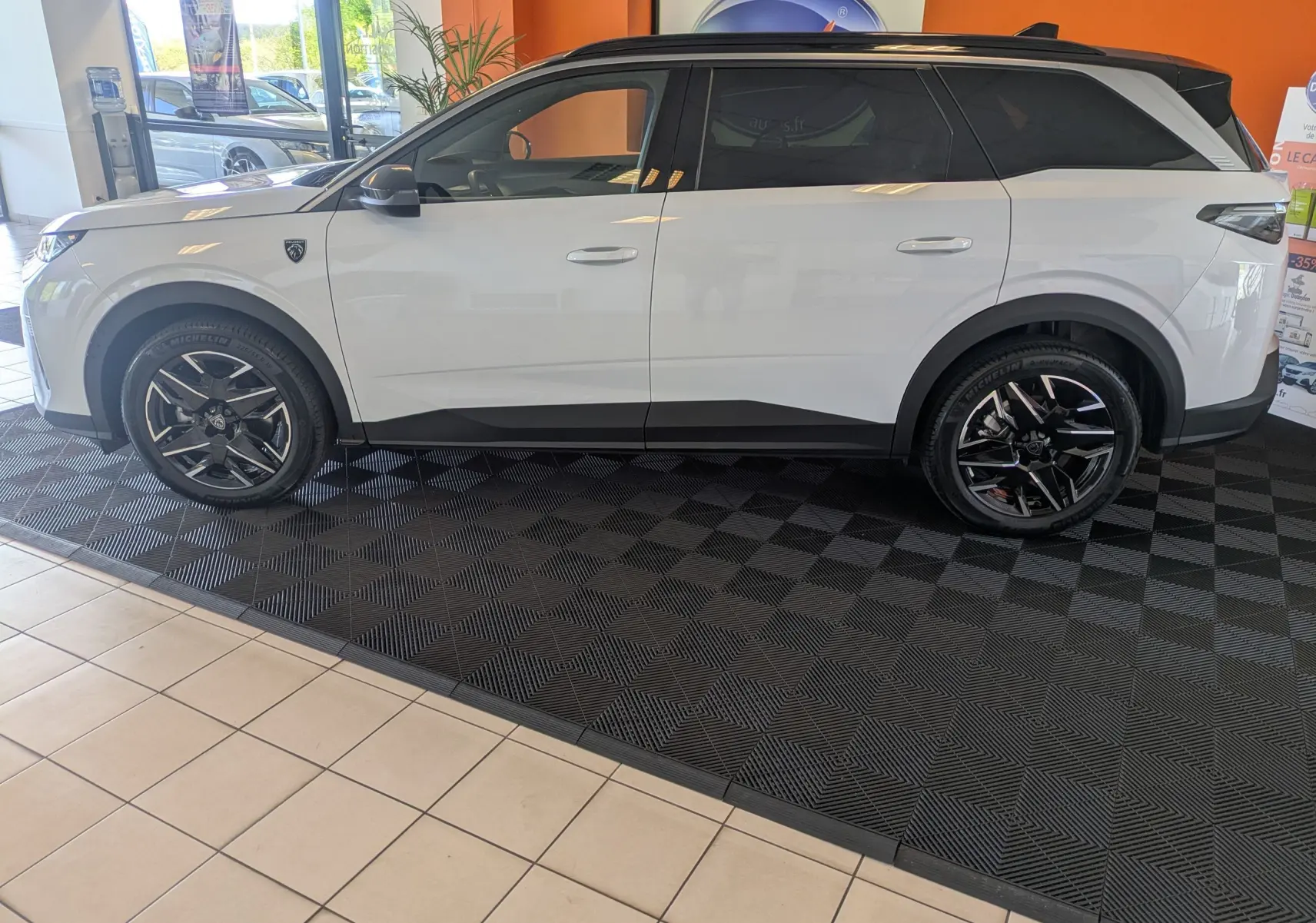 Peugeot 5008 Hybrid 145 e-DCS6 GT blanc Okenite avec toit noir, vue de profil côté gauche en intérieur showroom.