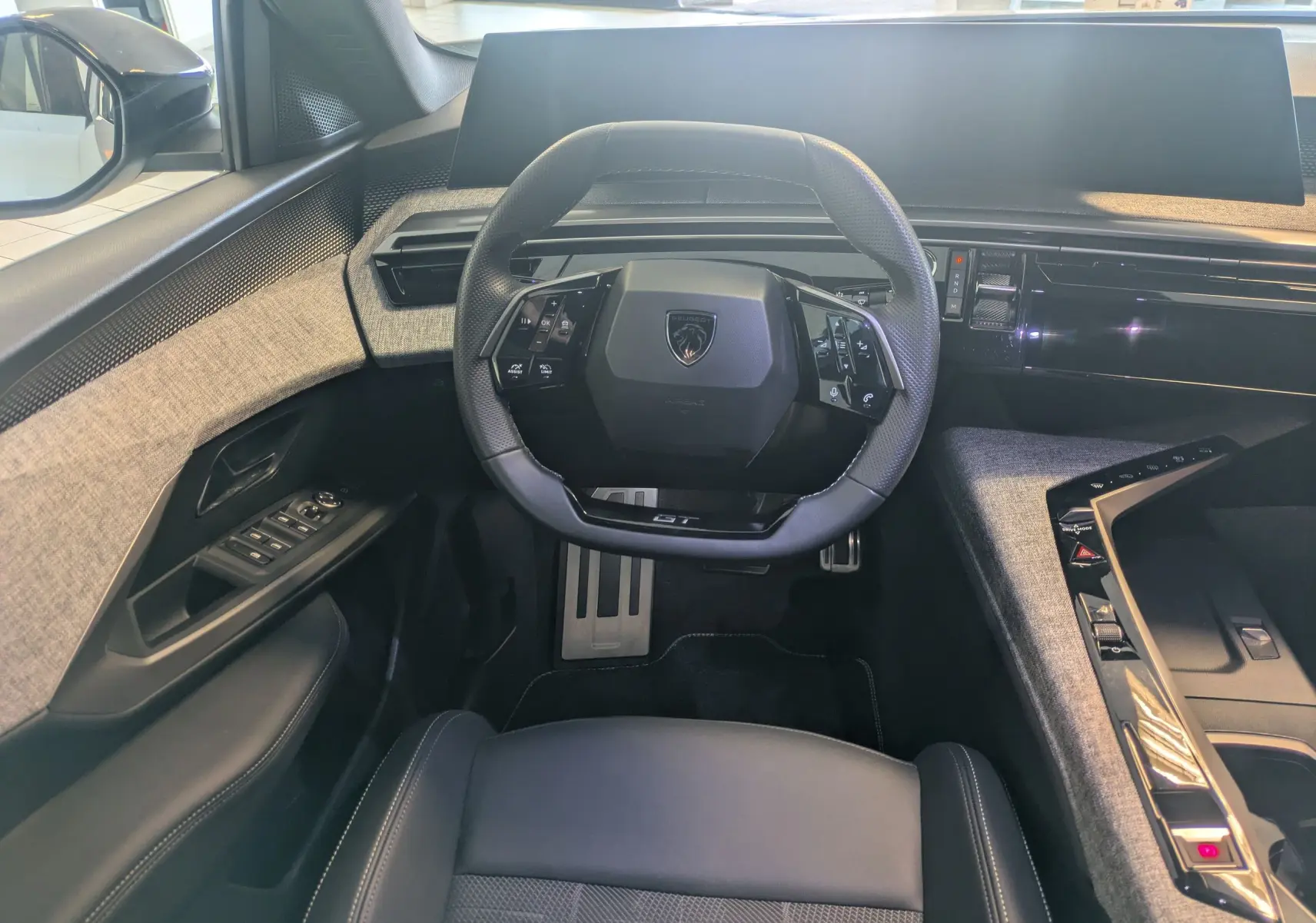 Vue intérieure frontale du Peugeot 5008 Hybrid 145 GT avec volant compact, tableau de bord numérique et habillage tissu gris.
