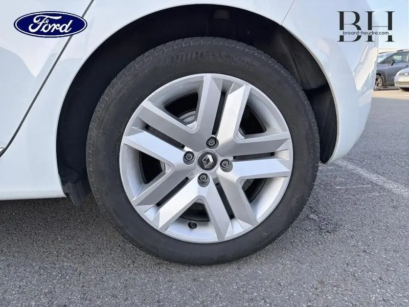 Gros plan sur la roue arrière droite blanche d'une Renault Clio 1.6 E-Tech 140ch avec jante alliage et logo Renault au centre.