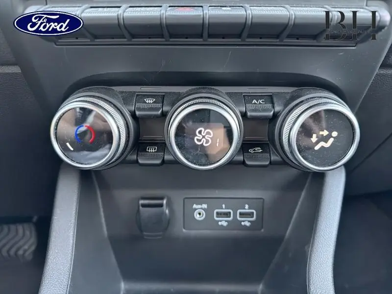 Gros plan sur les commandes de climatisation et les ports USB d'une Renault Clio blanche, version 1.6 E-Tech 140ch Business.