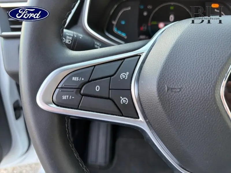 Gros plan sur les commandes de régulateur de vitesse au volant d'une Renault Clio blanche, version hybride 2021.