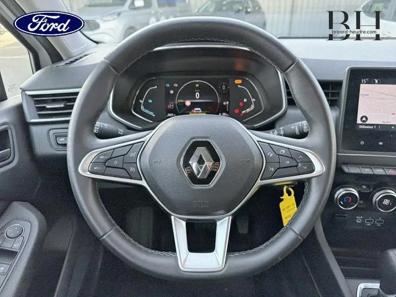 Vue intérieure centrée sur le volant noir de la Renault Clio 1.6 E-Tech avec tableau de bord numérique et écran tactile à droite.