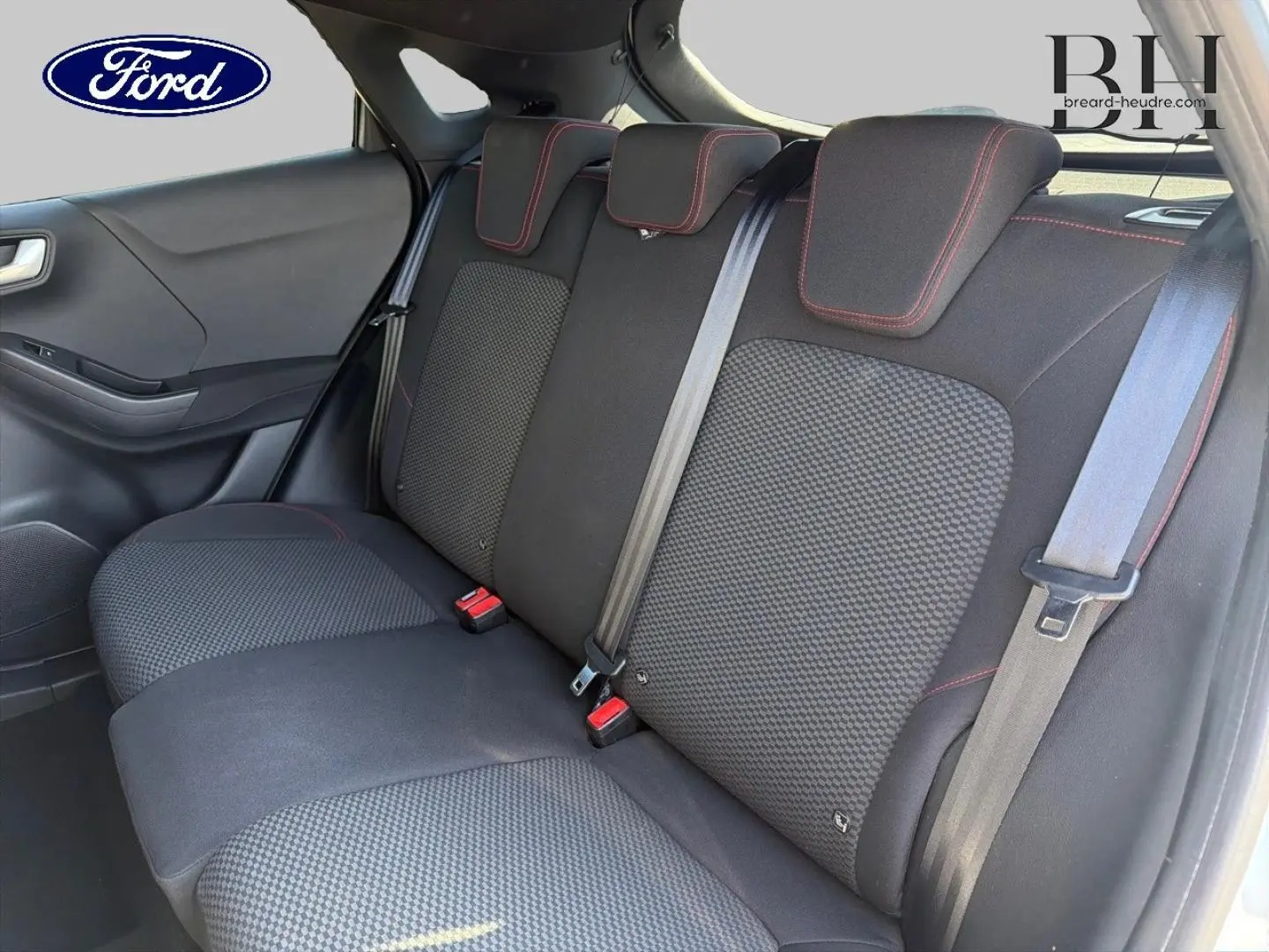Vue intérieure du siège arrière droit de la Ford Puma 2023 avec tissu noir et surpiqûres rouges visibles.