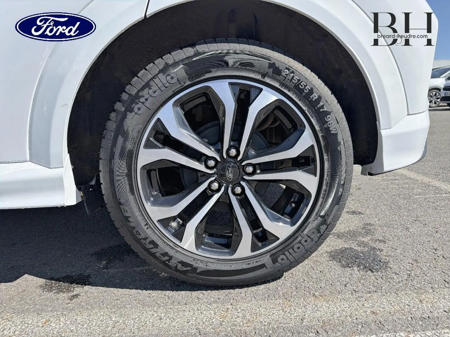 Gros plan sur la roue avant droite du Ford Puma blanc Glacier avec jante alliage bicolore et logo Ford central.