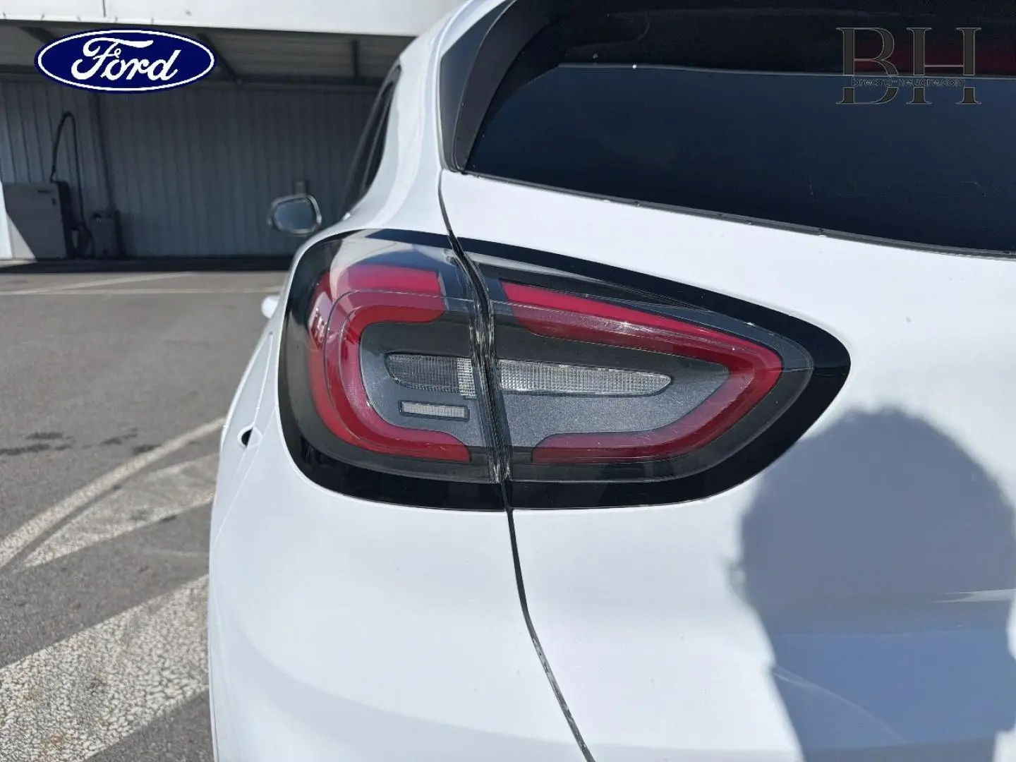 Gros plan sur le feu arrière gauche du Ford Puma blanc Glacier, avec vitres arrière surteintées visibles.