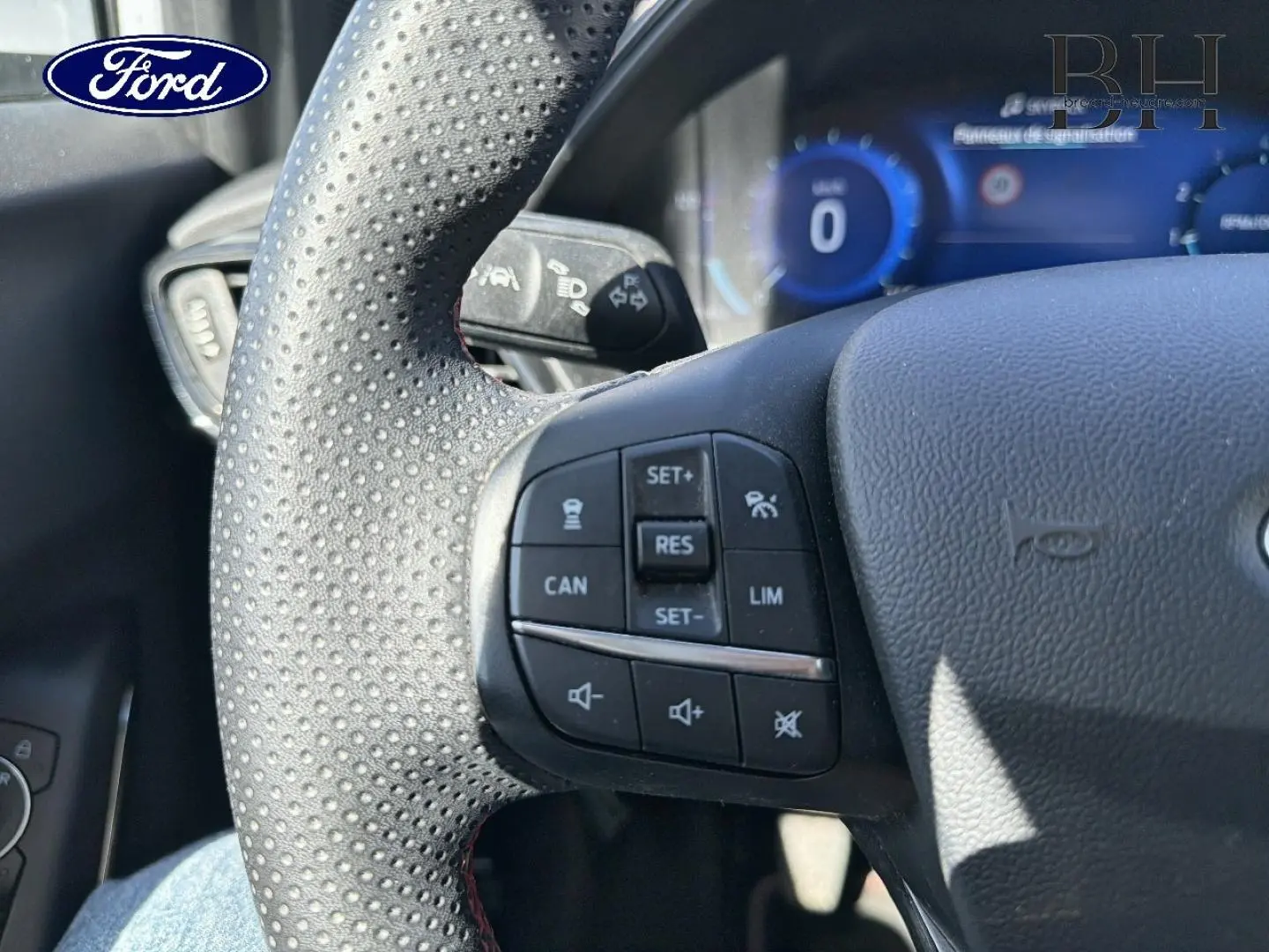 Vue rapprochée du volant sport perforé avec commandes multifonctions du Ford Puma 2023, ambiance intérieure noire.