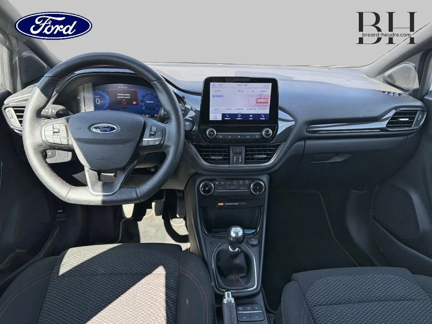 Vue intérieure avant du Ford Puma 2023 montrant le volant multifonction, écran tactile central et levier de vitesse manuel.