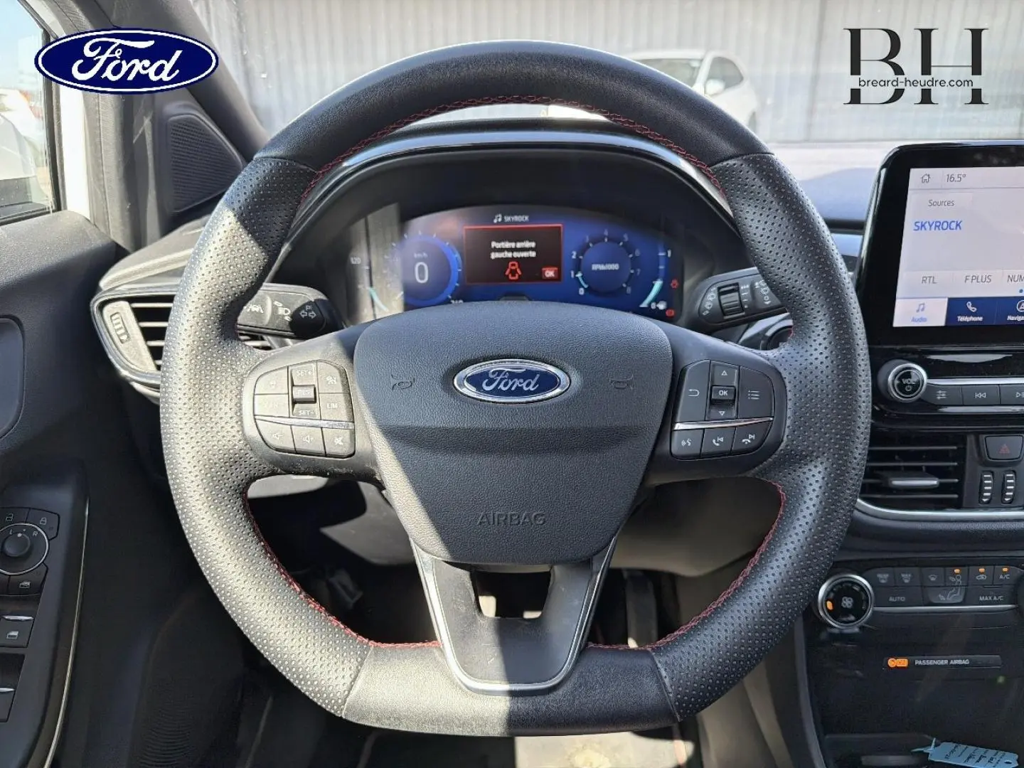 Vue rapprochée du volant sport en cuir noir avec surpiqûres rouges du Ford Puma 2023, tableau de bord digital et écran tactile visibles.