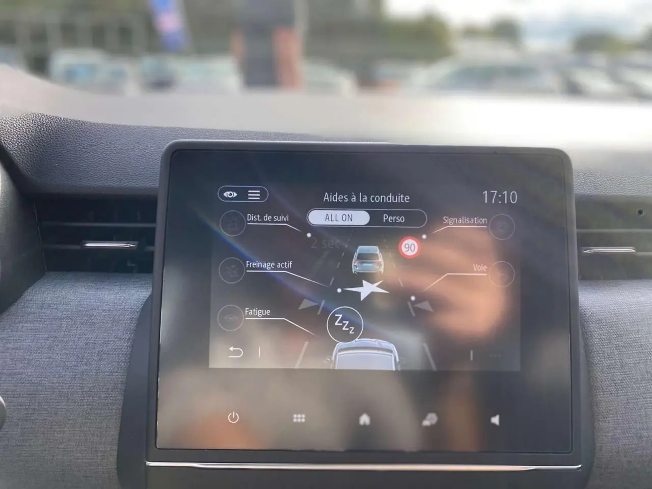 Écran tactile central de la Renault Clio 2025 montrant les aides à la conduite dans un intérieur sombre.