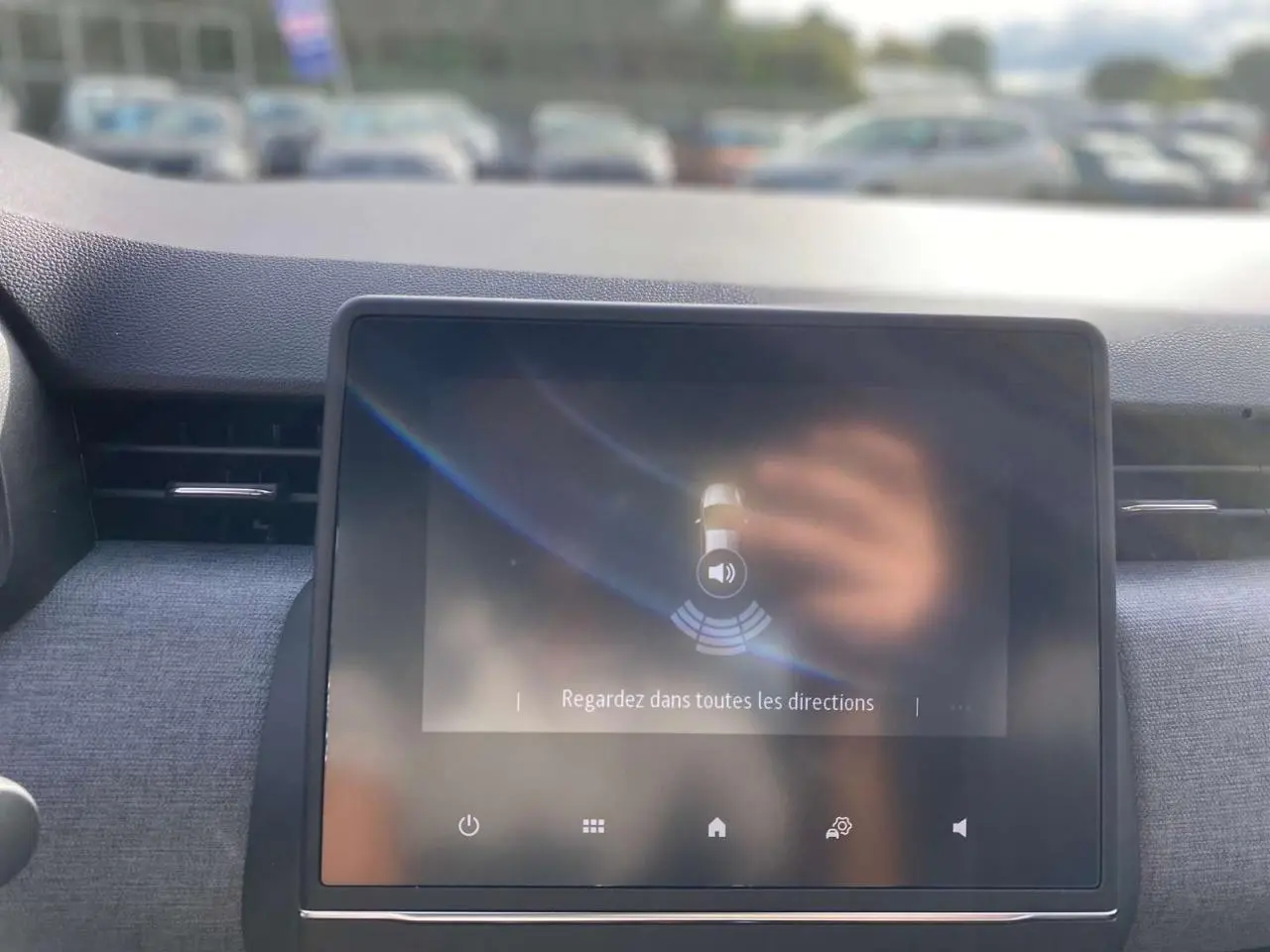 Écran tactile central de la Renault Clio 2025 affichant l'aide au stationnement arrière dans un intérieur gris.