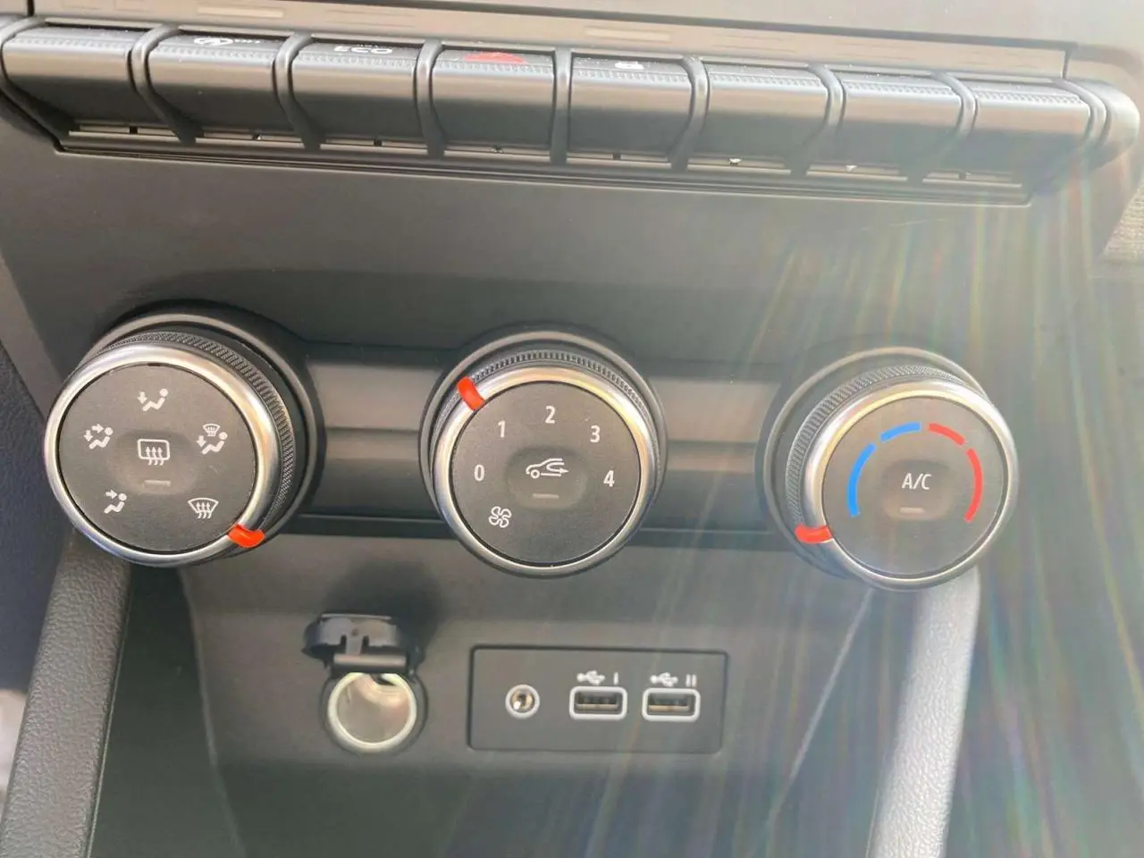 Gros plan sur les commandes de climatisation manuelle et ports USB de la Renault Clio Evolution 2025 en intérieur.