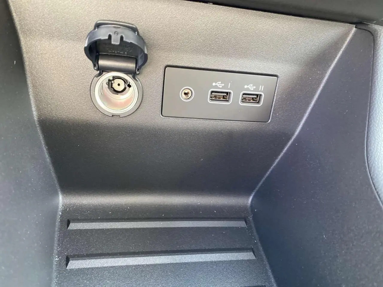 Prise allume-cigare et double port USB visibles dans le rangement intérieur de la Renault Clio Evolution noire étoile 2025.