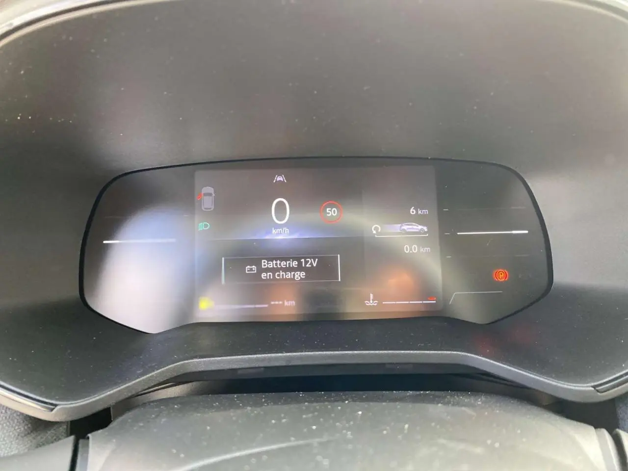 Tableau de bord numérique de Renault Clio 2025 affichant vitesse, alertes et batterie en charge, vue frontale intérieure.