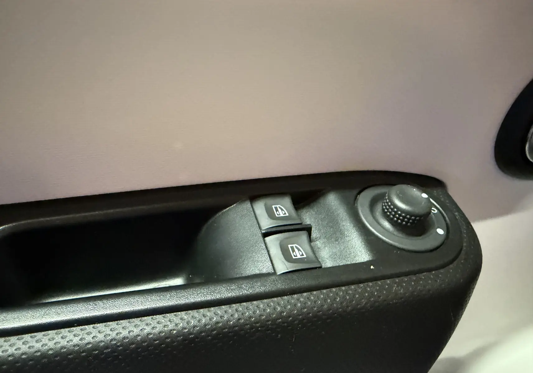 Gros plan sur les commandes de réglage des vitres et des rétroviseurs côté conducteur d'une Renault Twingo III gris.