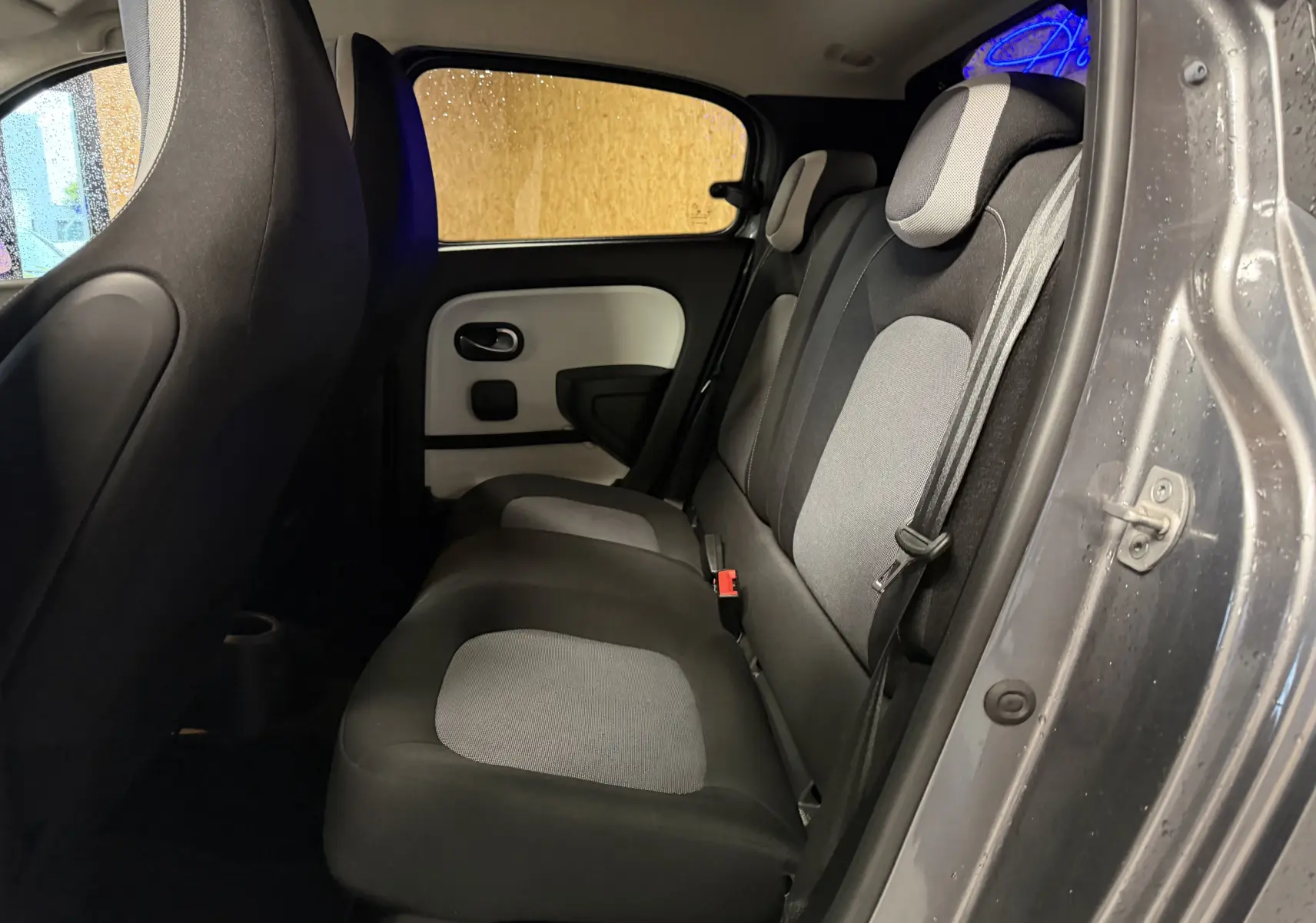 Vue intérieure côté droit des sièges arrière gris et noir de la Renault Twingo III 2018 avec porte ouverte.
