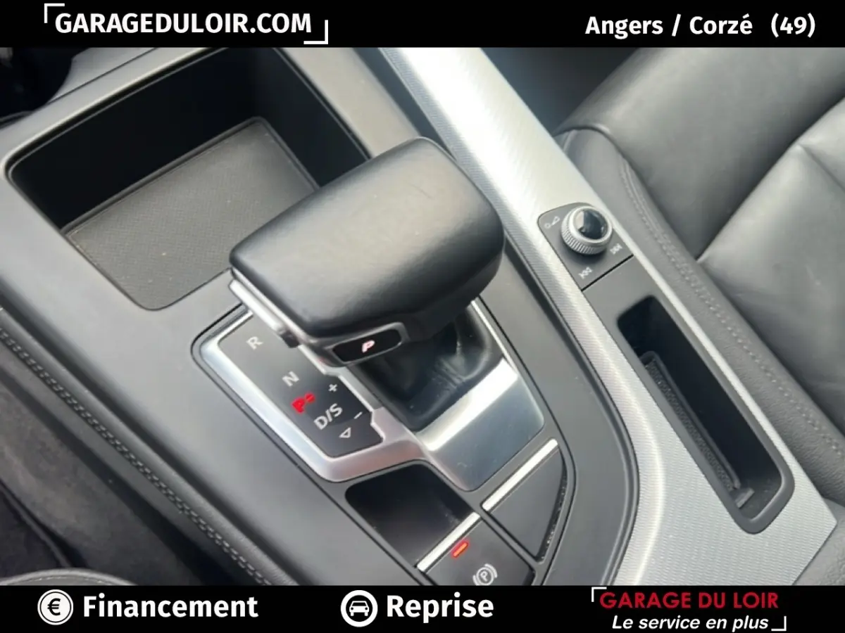 Gros plan sur la console centrale noire de l'Audi A4 40 TFSI, mettant en valeur le levier de vitesse automatique et les commandes adjacentes.