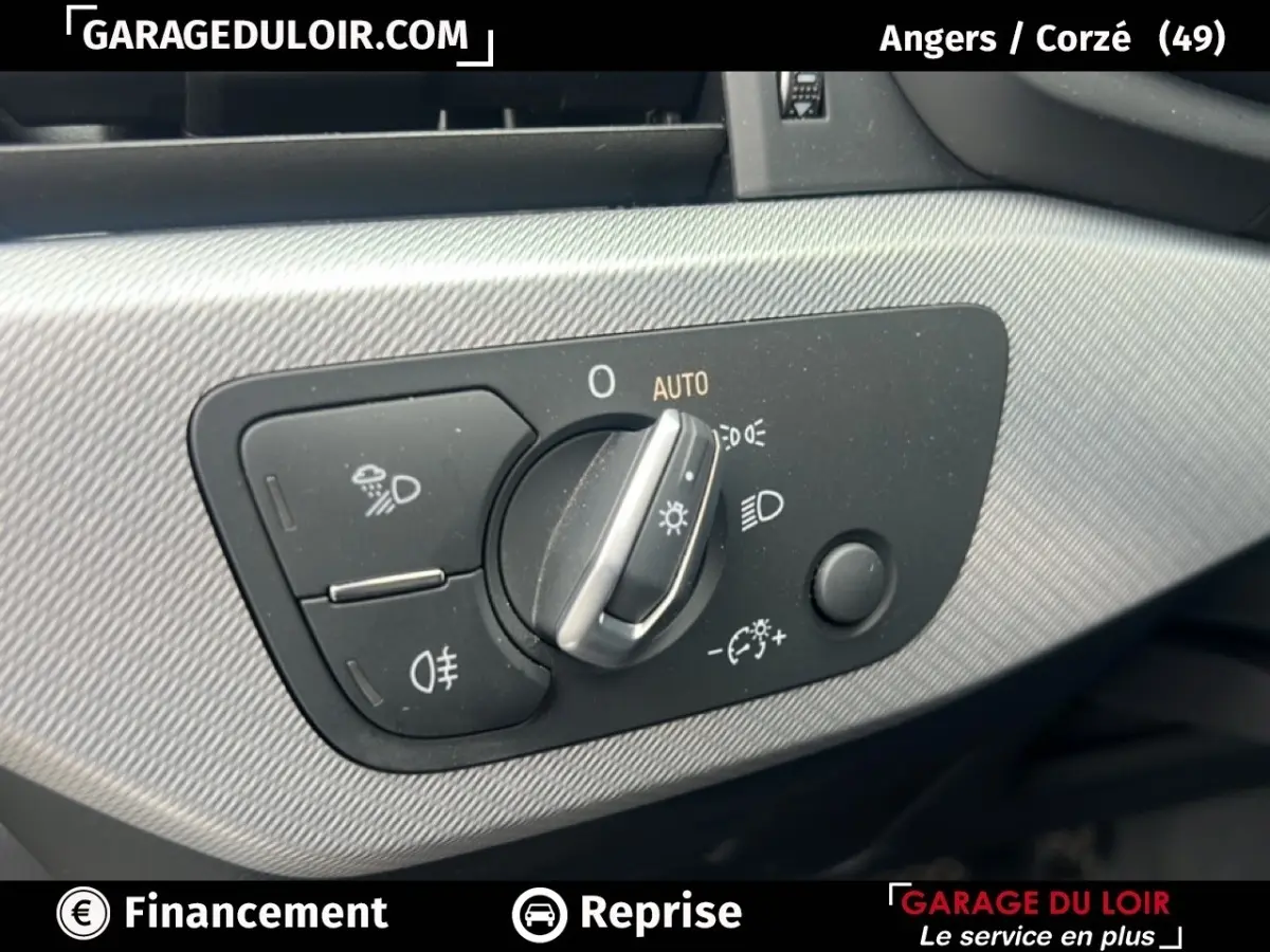 Gros plan sur la commande des phares à gauche du tableau de bord d'une Audi A4 noire, avec réglage automatique et antibrouillard.