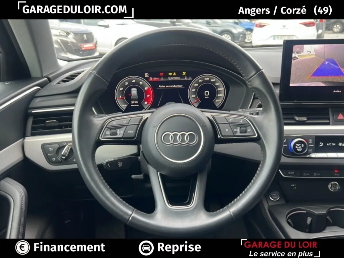 Vue intérieure centrée sur le volant cuir noir et le tableau de bord numérique d'une Audi A4 noire de 2020.