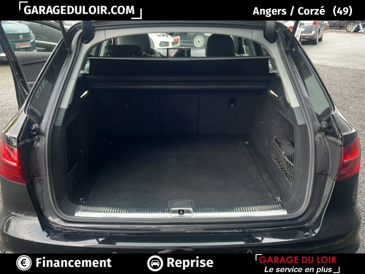 Coffre ouvert d’une Audi A4 noire vue de l’arrière, montrant l’espace de chargement et la plage arrière.