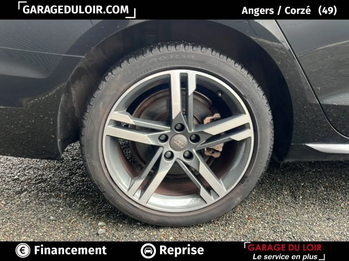 Gros plan sur la roue arrière droite d'une Audi A4 noire, mettant en valeur la jante alliage cinq branches.