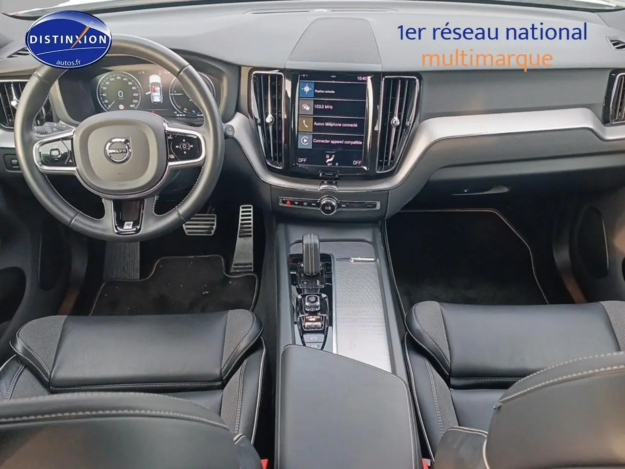 Vue intérieure avant du Volvo XC60 blanc 2021, tableau de bord moderne avec écran tactile central et volant cuir multifonction.