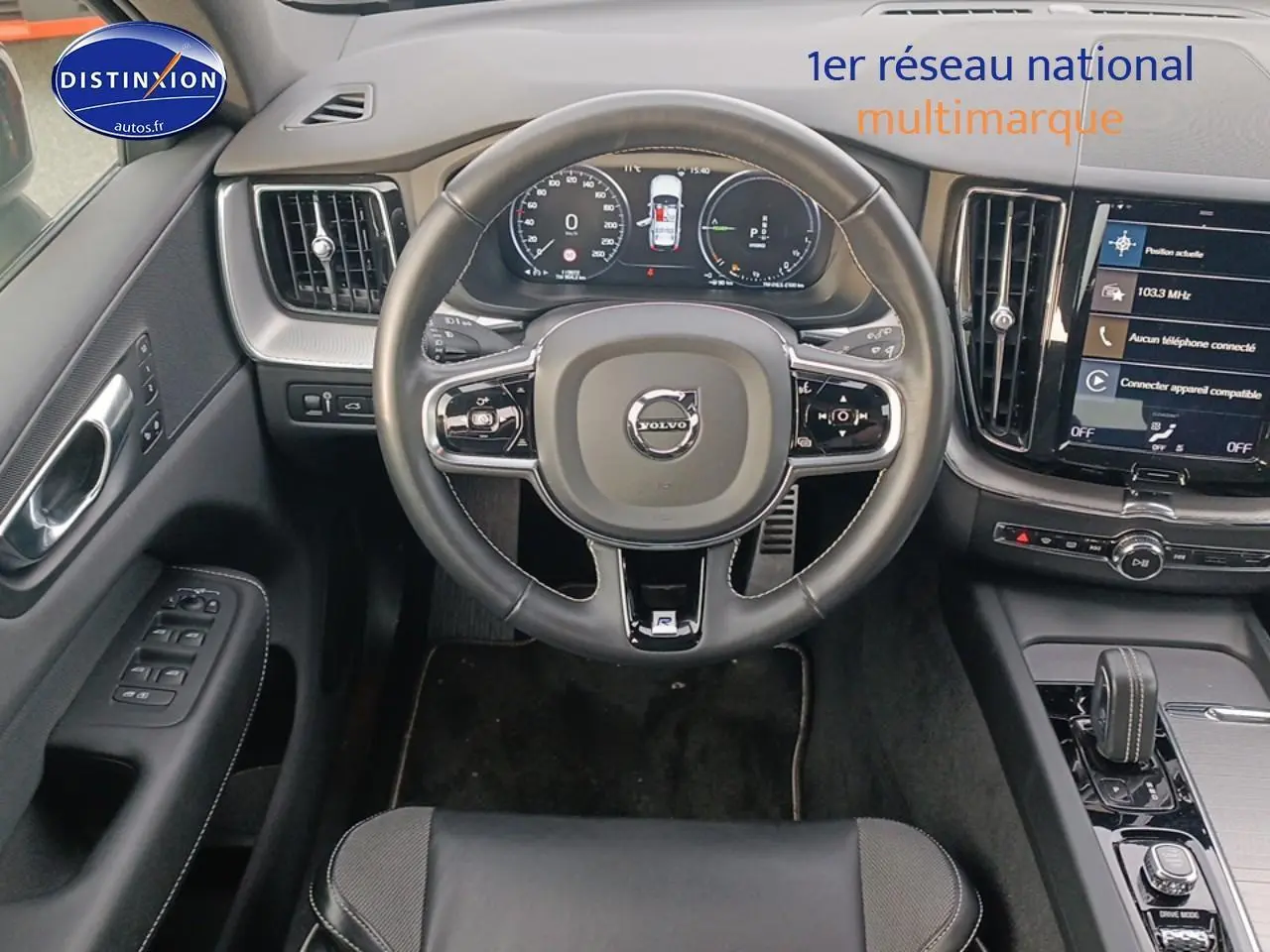 Vue intérieure frontale du volant cuir noir et tableau de bord numérique du Volvo XC60 blanc 2021.