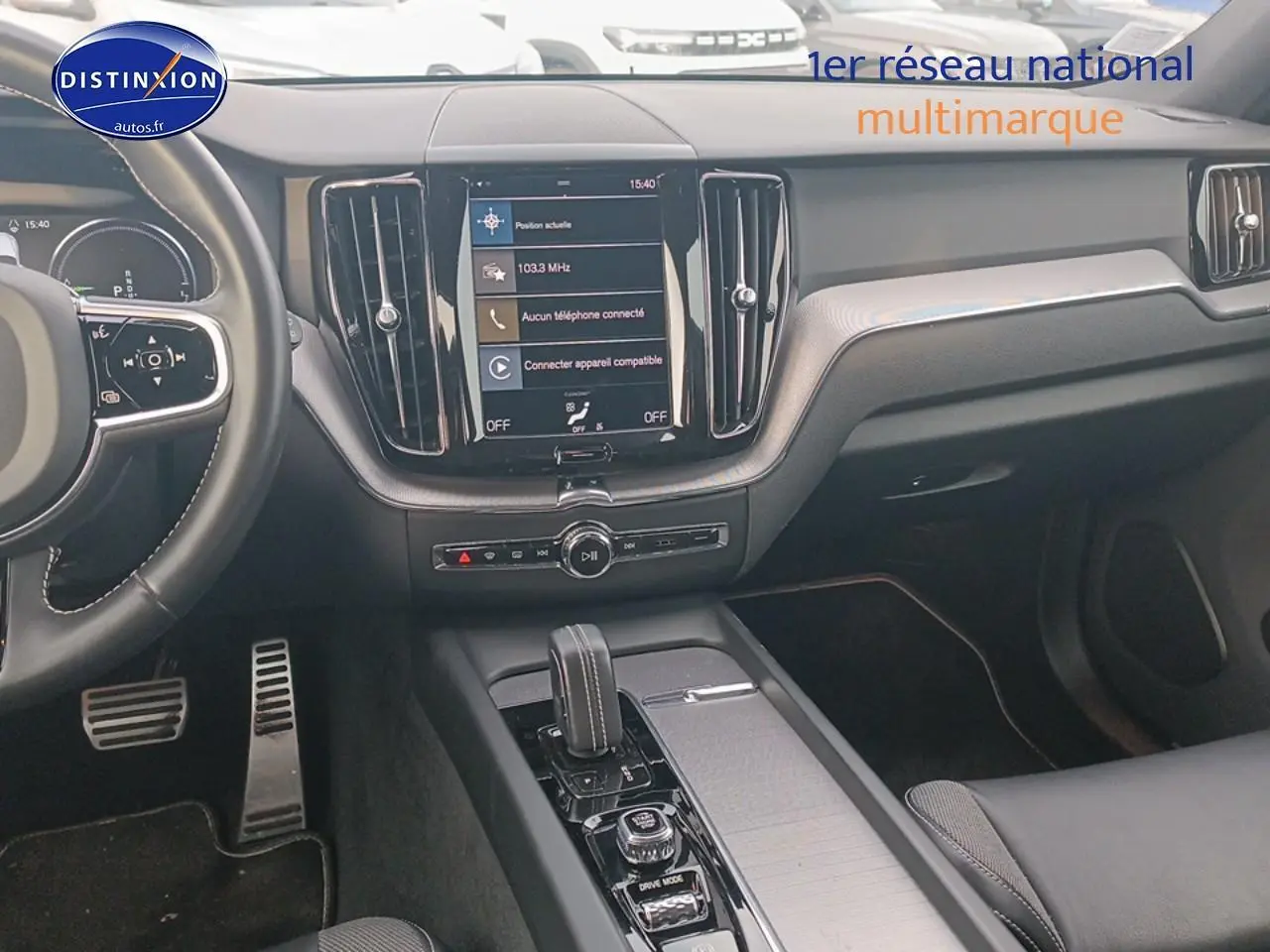 Vue intérieure du tableau de bord et console centrale du Volvo XC60 blanc, avec écran tactile et volant multifonction.