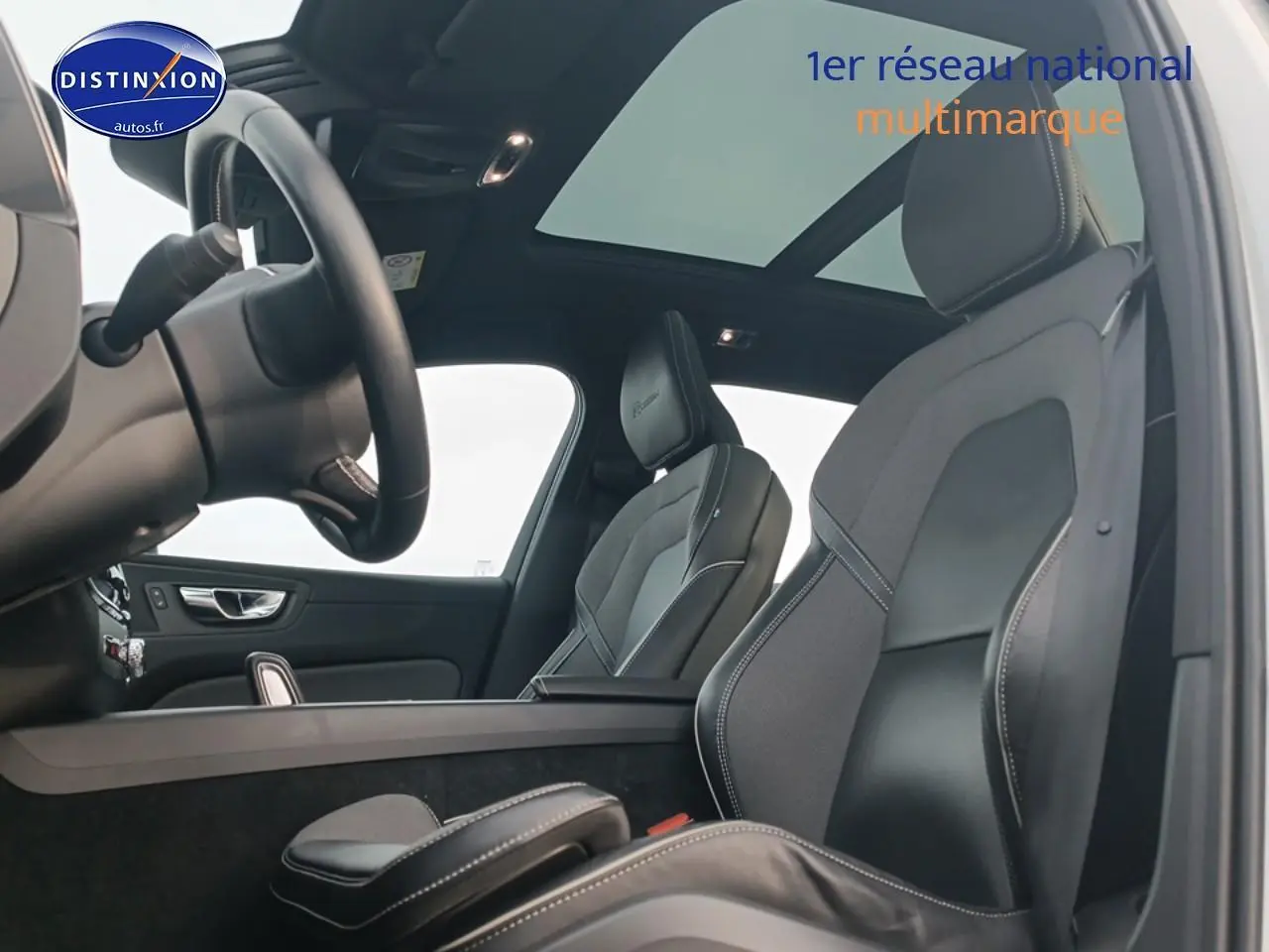 Vue intérieure côté conducteur du Volvo XC60 2.0 T8 blanc, mettant en valeur les sièges sport et le toit panoramique.