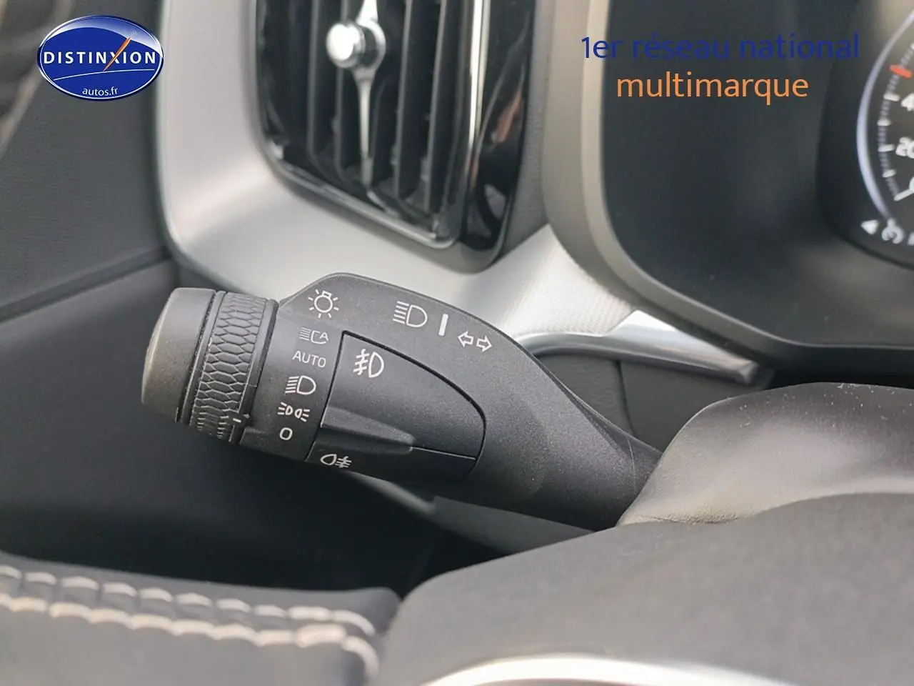 Gros plan sur la commande des feux et clignotants à gauche du volant dans l'habitacle du Volvo XC60 blanc.