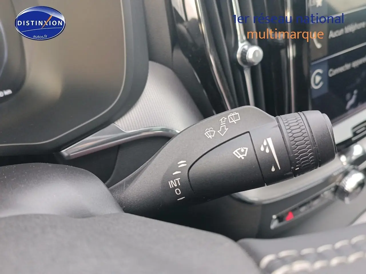 Gros plan sur la commande des essuie-glaces dans l’habitacle d’un Volvo XC60 blanc, avec tableau de bord partiellement visible.