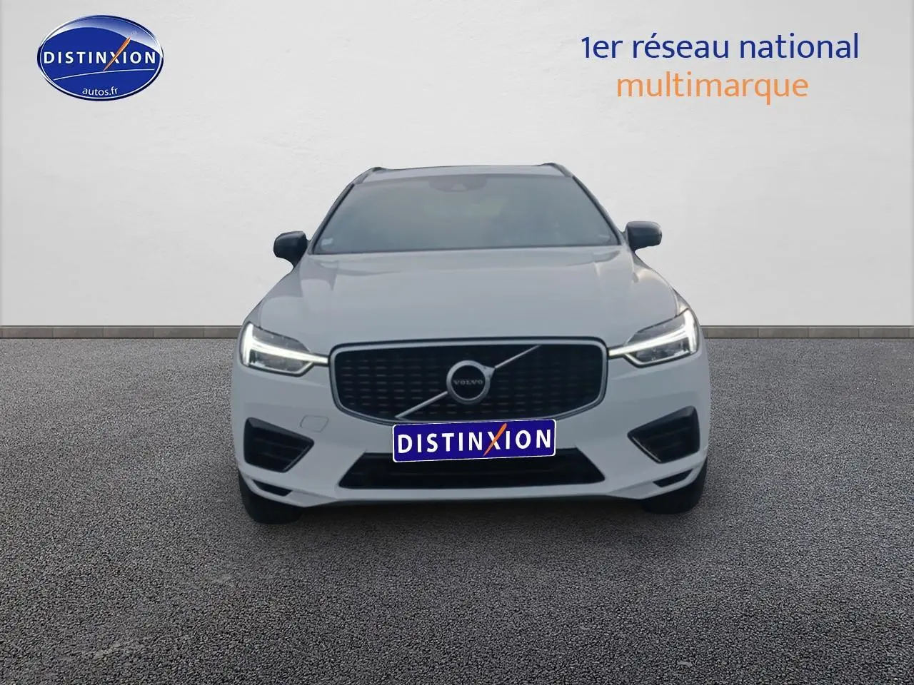 Vue frontale d'un Volvo XC60 blanc avec calandre noire et phares LED allumés sur fond neutre.