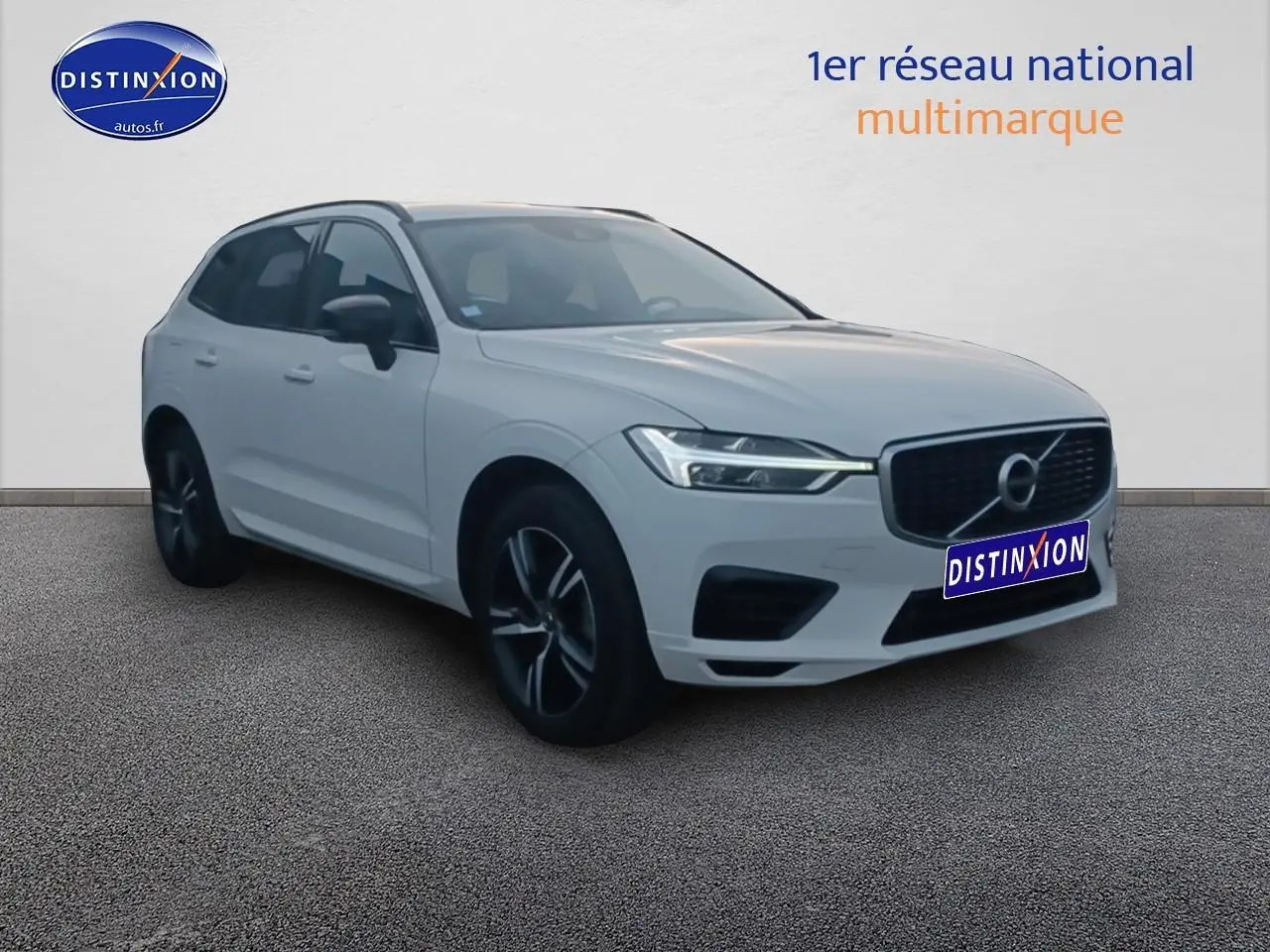 Volvo XC60 blanc en 3/4 avant droit, avec calandre noire et jantes alliage foncé visibles.