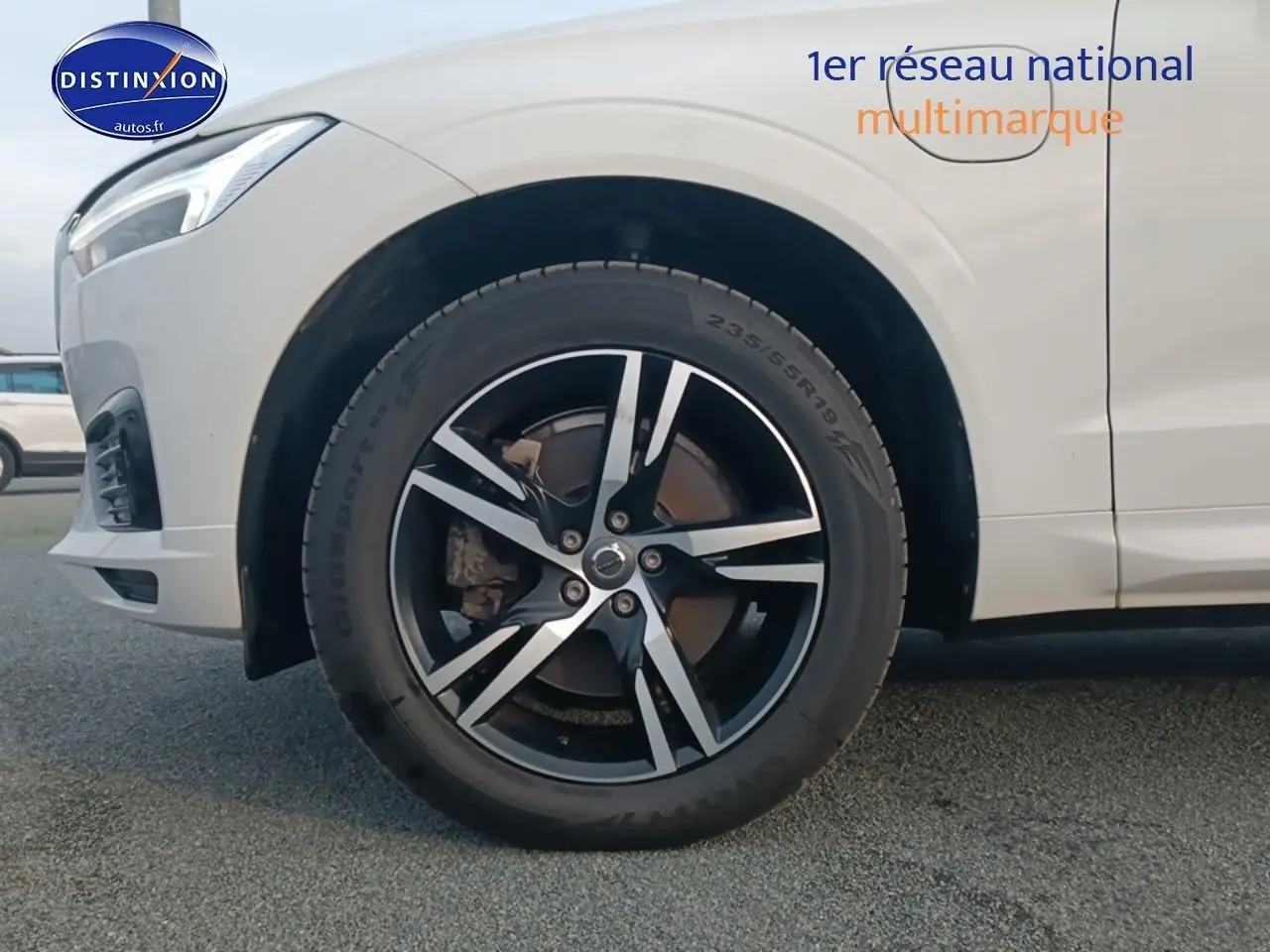 Gros plan sur la roue avant gauche d’un Volvo XC60 blanc, jante alliage noir et argentée design sportif.