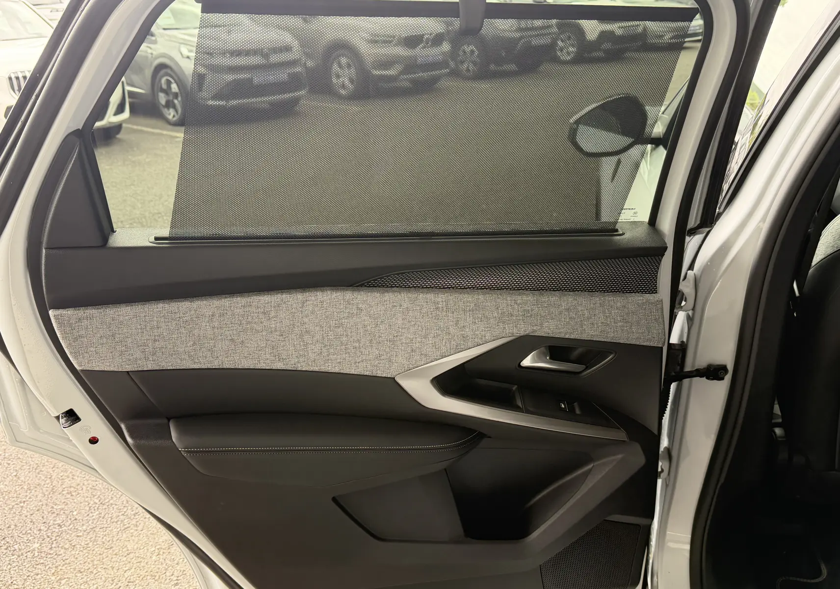 Vue intérieure de la porte arrière droite blanche du Peugeot 5008 Hybrid 145 GT avec pare-soleil et garniture tissu gris.