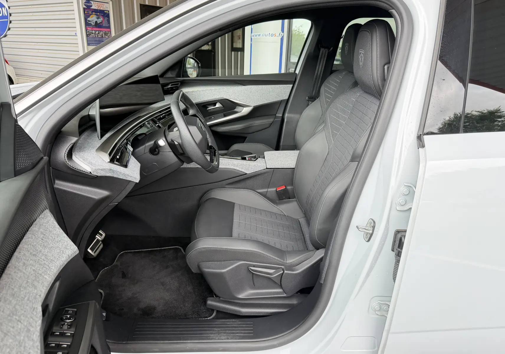 Vue intérieure côté conducteur du Peugeot 5008 Hybrid 145 e-DCS6 GT blanc, sièges tissu/tep gris avec surpiqûres Iced Clay.