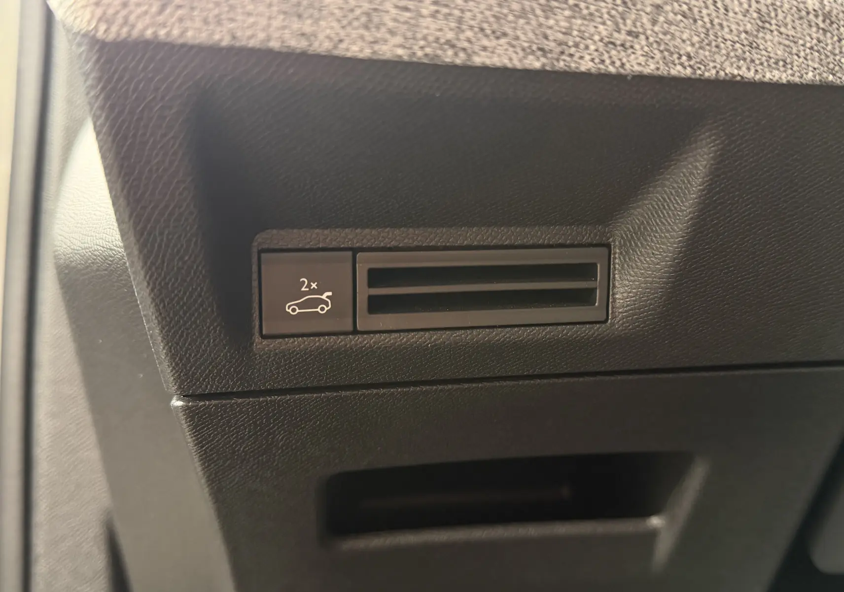 Gros plan sur le bouton d'ouverture électrique du hayon dans l'habitacle noir du Peugeot 5008 Hybrid 145 e-DCS6 GT.