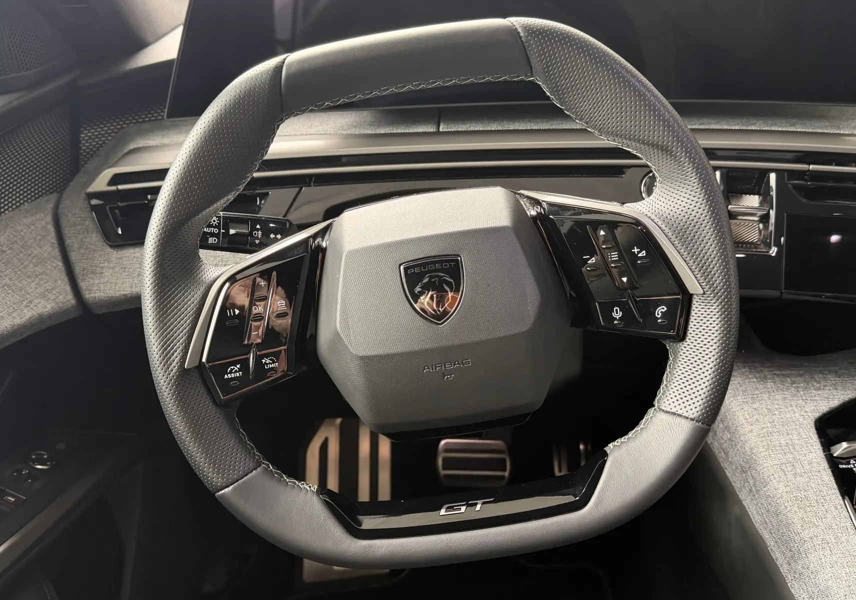 Gros plan sur le volant cuir perforé noir avec logo Peugeot et inscription GT du Peugeot 5008 Hybrid 145 e-DCS6 GT.