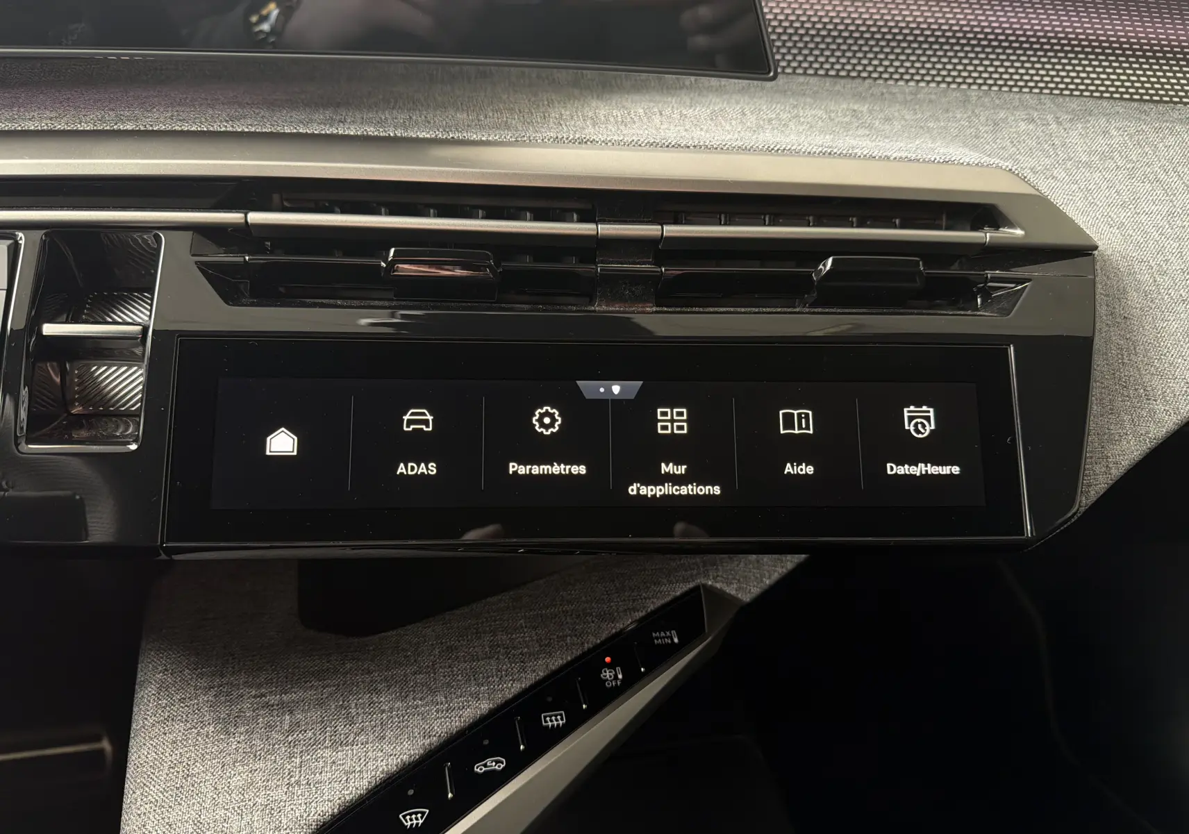 Vue rapprochée de l’écran tactile central et de la console avec commandes tactiles dans l’habitacle gris du Peugeot 5008 Hybrid 2025.