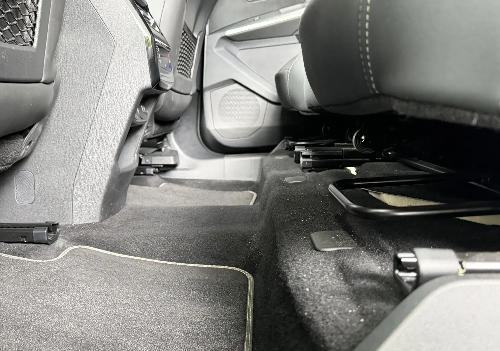 Vue intérieure sous les sièges avant du Peugeot 5008 Hybrid 145 e-DCS6 GT, tapis noir avec surpiqûres claires visibles.
