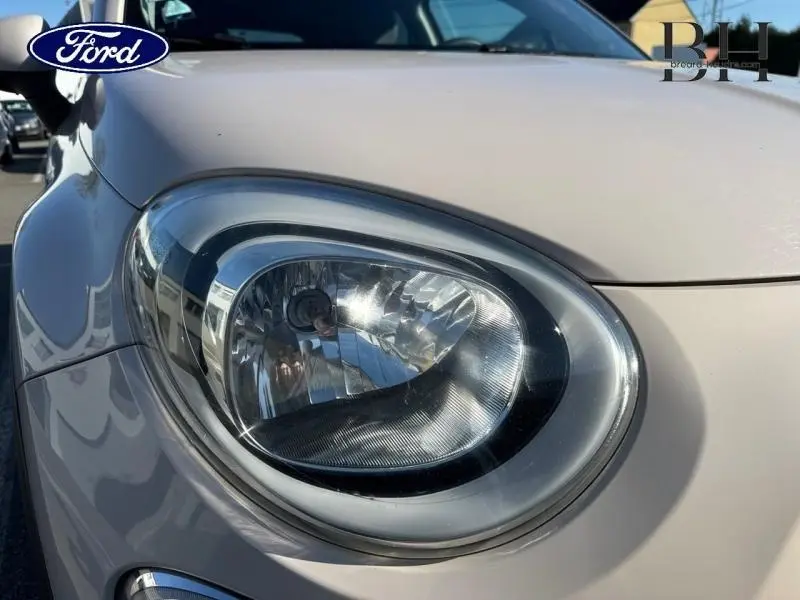 Gros plan sur le phare avant droit argenté d'une FIAT 500X 2015, soulignant ses lignes arrondies et détails lumineux.