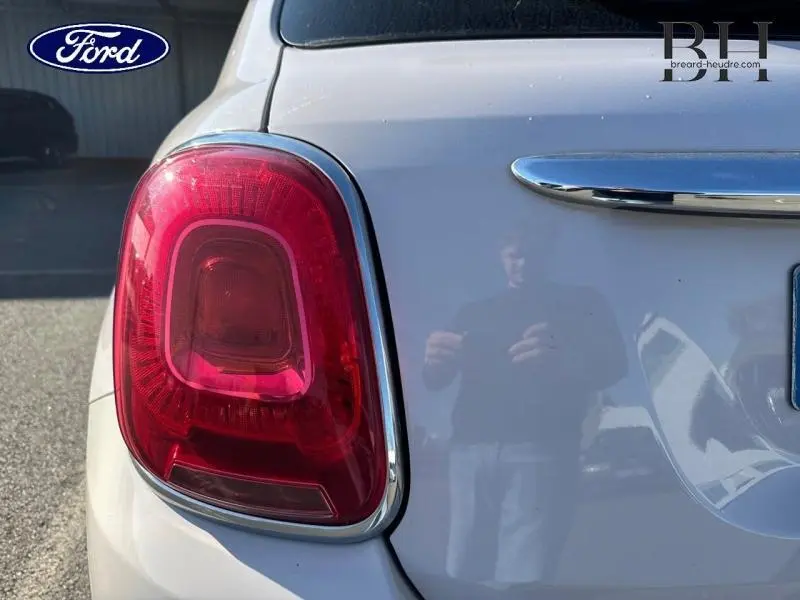 Gros plan sur le feu arrière gauche d’une FIAT 500X argentée, avec reflet sur la carrosserie lisse.