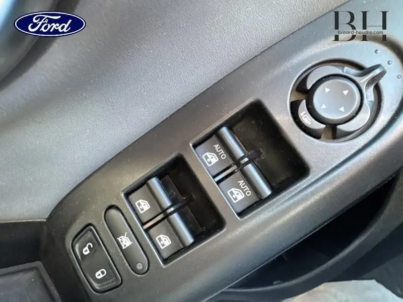 Gros plan sur les commandes de lève-vitres et réglage des rétroviseurs côté conducteur d'une FIAT 500X argentée.