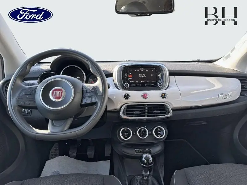 Tableau de bord argenté et volant cuir multifonction d'une Fiat 500X vue de face, avec écran tactile central.
