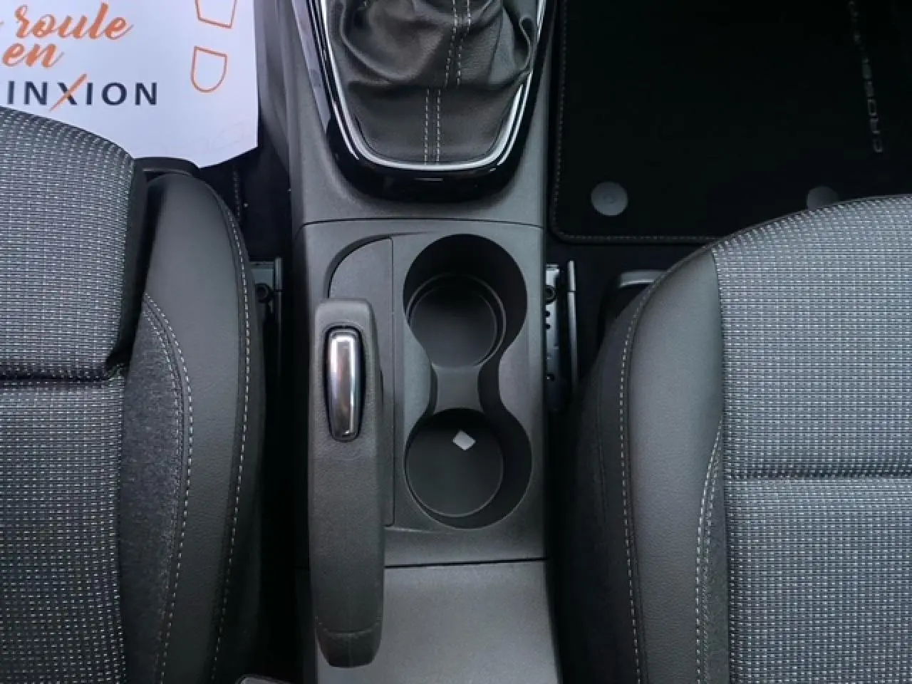 Vue plongeante sur la console centrale intérieure de l'Opel Crossland gris Magnetic, montrant levier de vitesse et porte-gobelets.