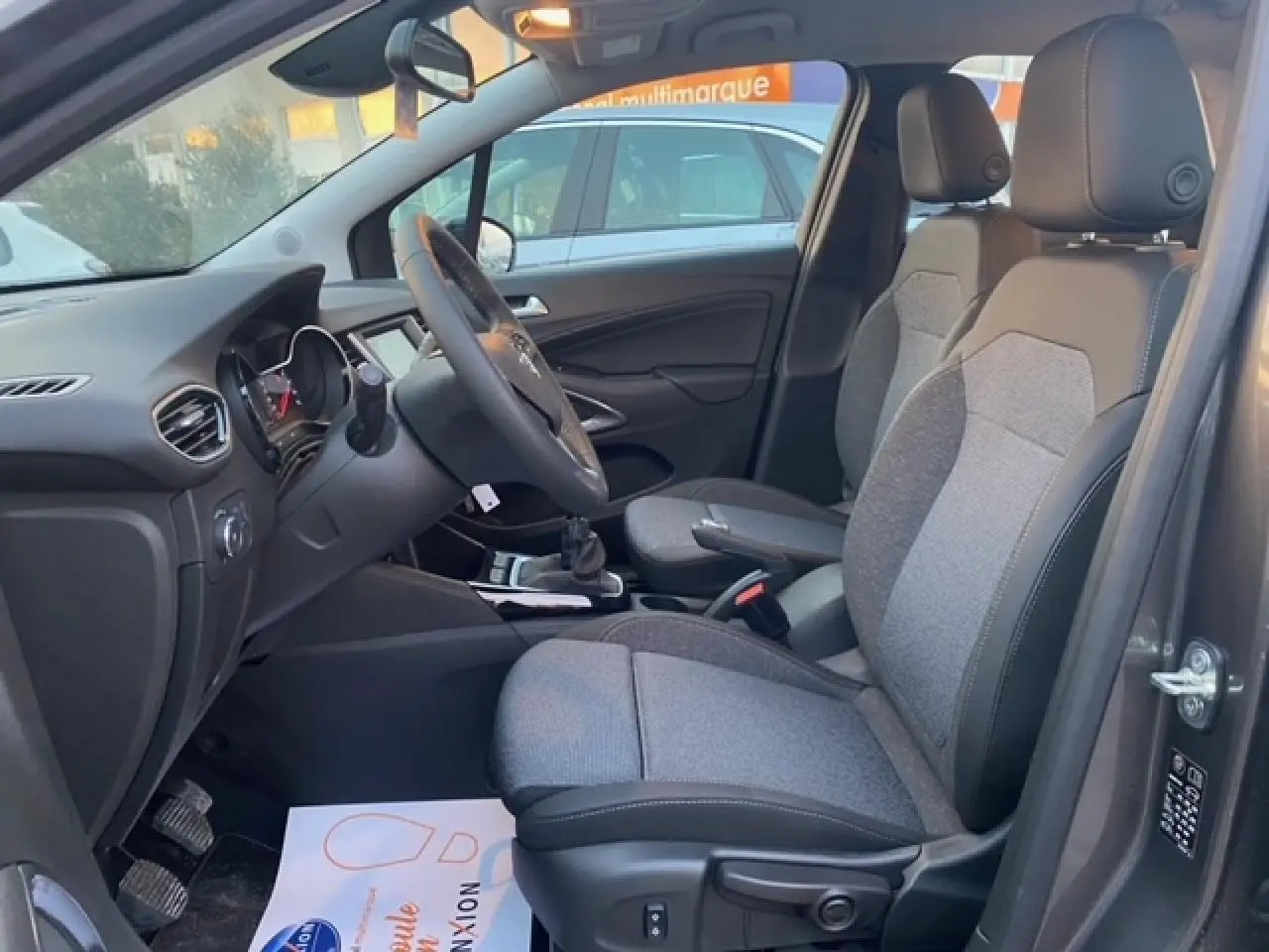 Vue intérieure côté conducteur de l’Opel Crossland gris Magnetic 2022, sièges tissu bicolore et volant multifonction.