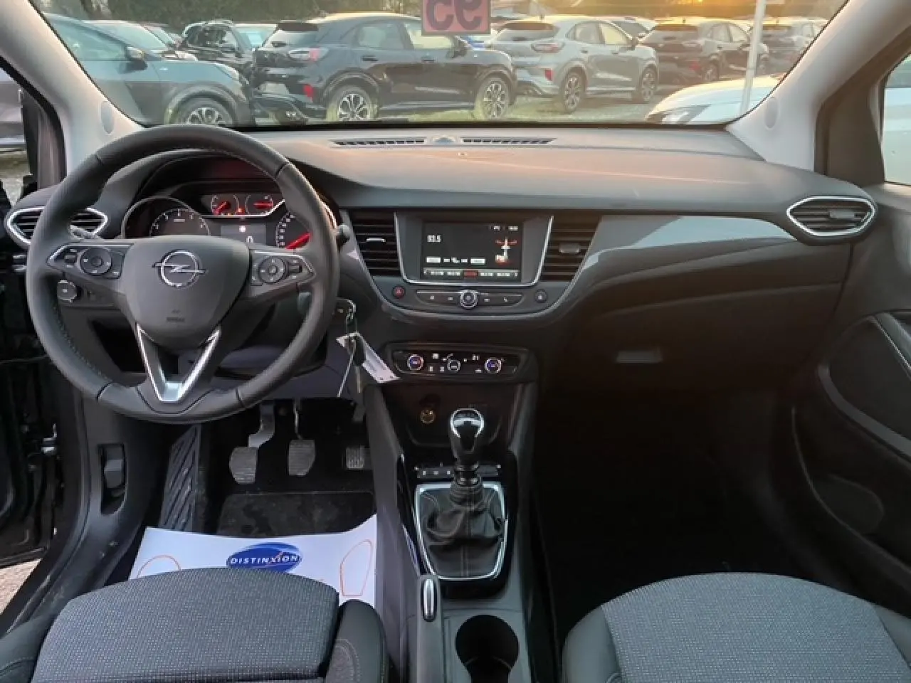 Vue intérieure avant de l'Opel Crossland gris Magnetic 2022, avec volant multifonction et boîte manuelle au premier plan.